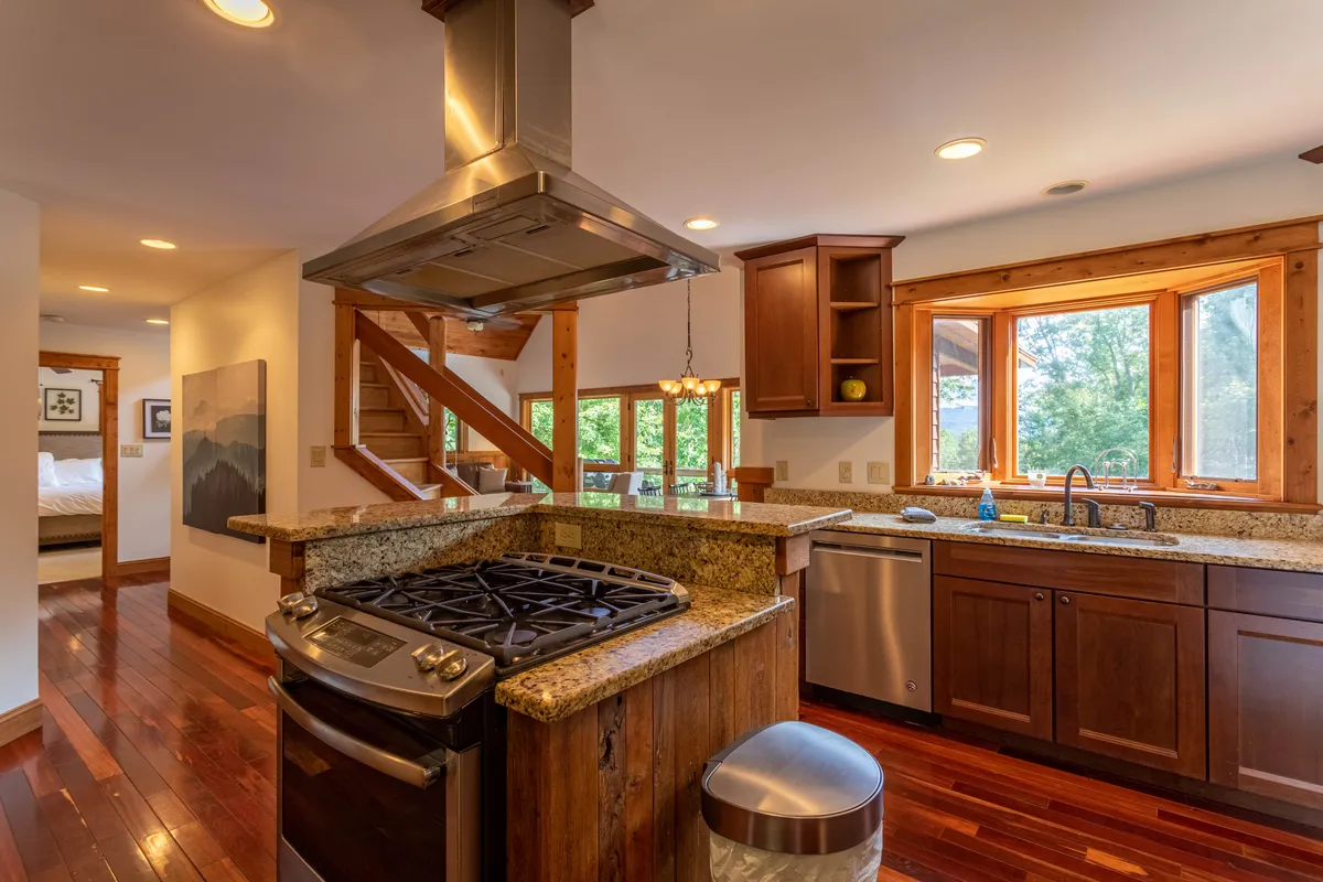 A bright kitchen scene with a gleaming granite island at its center, surrounded by stainless steel appliances, wooden cabinetry, and generous windows. The layout encourages social cooking, gathering, and morning routines, aligning perfectly with the idea of meal prep as a shared experience.